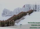 Liels skaits karavīru zaļās formās stāv rindās uz sniegotiem pakāpieniem ziemas ainavā ar kokiem, pieminekli un Latvijas karogiem fonā. Augšējos stūros ir divas militārās emblēmas, bet attēla apakšējā labajā pusē teksts: "Nacionālo bruņoto spēku Kājnieku skolas aktivitātes JANVĀRĪ".