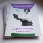 Brošūru kaudze. Uz augšējās brošūras vāka redzama gados vecāka sieviete, kas tur klēpjdatoru. Teksts uz vāka: "Digitālo prasmju programma" un "PIESAKIES BEZMAKSAS MĀCĪBĀM un apgūsti digitālās prasmes jau šodien!".