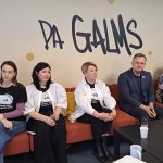 Pieci cilvēki, četras sievietes un viens vīrietis, sēž uz oranža dīvāna un uzmanīgi klausās vai vēro. Uz sienas aiz viņiem ir liels uzraksts "PA GALMS". Trīs sievietes valkā melnus T-kreklus ar baltu logotipu "PA GALMS ALŪKSNES BĒRNU UN JAUNIEŠU CENTRS". Priekšā atrodas galds ar dzērieniem un klēpjdatoru.