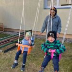 Bērna roka zilā jakā stiepjas uz pelēku plastmasas grozu, kas pilns ar krāsainām Lieldienu puzles detaļām. Detaļās attēlotas dekorētas olas un multfilmu dzīvnieki, piemēram, zaķi un vardes, dažām ir skaitļi, piemēram, "6" un "3".