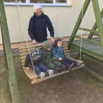 Bērna roka sniedzas pēc Lieldienu tēmas puzles gabaliņa no pelēka groza. Grozā ir daudz laminētu puzles detaļu ar krāsainām olām un multfilmu dzīvniekiem, piemēram, zaķiem un vardēm, uz dažām detaļām redzami cipari 3 un 6.