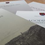 Vairāki baltas krāsas apbalvojumu dokumenti no Alūksnes novada pašvaldības, uz kuriem redzami uzraksti: "PAGODINĀJUMS SPORTĀ", "PAGODINĀJUMS KULTŪRĀ", "PAGODINĀJUMS IZGLĪTĪBĀ" un "PAGODINĀJUMS UZŅĒMĒJDARBĪBĀ". Priekšplānā esošajam dokumentam ir arī melnbalta pilsētas ilustrācija uz kalna.