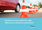 Sarkana automašīna uz asfalta ceļa, blakus virknē izvietoti oranži-balti satiksmes konusi. Attēla apakšdaļā uz gaiši zila fona balts teksts: "Pasākuma norises laikā 29. maijā Alūksnē būs satiksmes ierobežojumi" un Alūksnes novada logo.