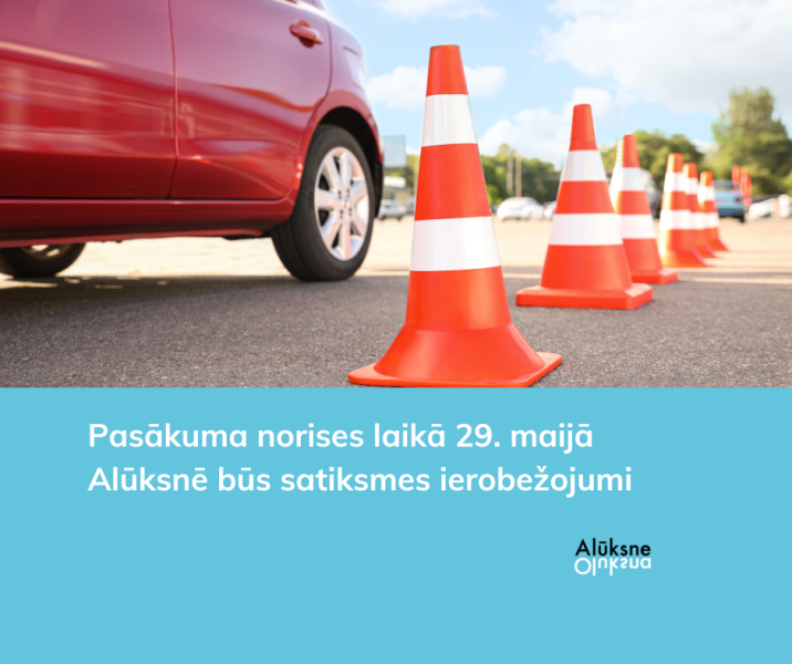Sarkana automašīna uz asfalta ceļa, blakus virknē izvietoti oranži-balti satiksmes konusi. Attēla apakšdaļā uz gaiši zila fona balts teksts: "Pasākuma norises laikā 29. maijā Alūksnē būs satiksmes ierobežojumi" un Alūksnes novada logo.
