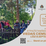 Vairāki cilvēki, galvenokārt vecāka gadagājuma, sēž ārā pie koka žoga mežainā vidē, lasot grāmatas. Attēla labajā pusē uz pelēka fona ir uzraksti "Latvijas Lauku Forums" un "Sabiedrības integrācijas fonds", oranžā kastītē teksts "# Viedais Ciems 2026", un lieliem burtiem "PIESAKIES ATPAZĪSTAMĪBAS ZĪMEI VIEDAIS CIEMS 2026 LĪDZ 8.SEPTEMBRIM"