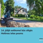 Zils ekskavators rok tranšeju uz Helēnas ielas, blakus redzamas izraktas zemes un būvgružu kaudzes. Ceļa posms ir norobežots ar sarkanbaltu lentu. Attēla apakšējā daļā ir teksts: "14. jūlijā satiksmei būs slēgts Helēnas ielas posms".